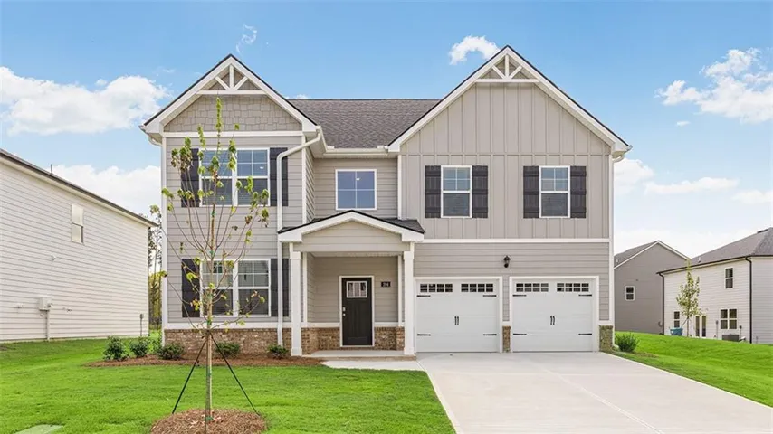 Two-story residence featuring light gray siding, white trim, a covered entry, and a two-car garage with paneling