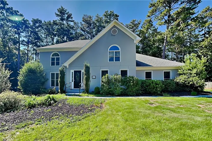 Stucco exterior with a peaked roofline, arched window, and mature landscaping