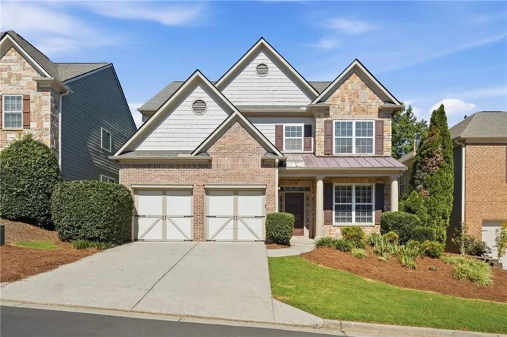 Brick and stone-clad exterior with dormer windows, a two-car garage, and a covered entry