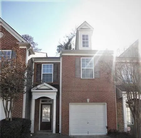 Brick facade residence featuring a single-car garage, dormer window, decorative window shutters, and a covered entry