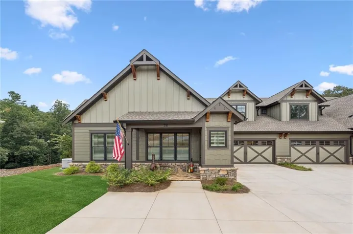 Craftsman-style exterior with board-and-batten and horizontal siding, stone accents, multiple gables, and two-car garages with decorative cross-bracing