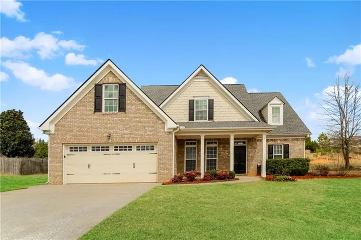 Brick and siding exterior with a covered entry, two-car garage, and established landscaping
