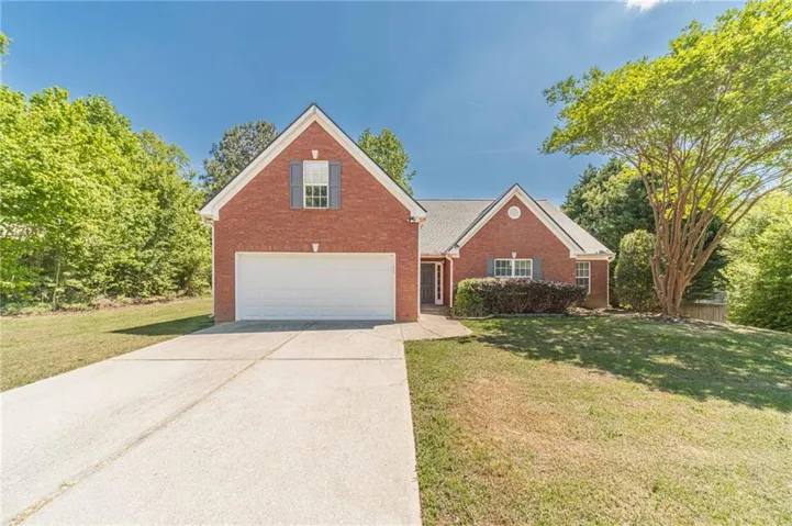 Brick exterior residence featuring an attached two-car garage, a concrete driveway, and a gabled roof