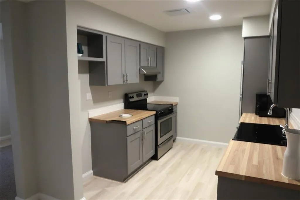 Kitchen with butcher block countertops, gray cabinets, electric range, and light wood-type flooring