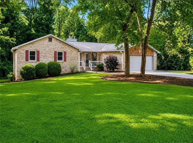 Brick exterior residence featuring a front lawn and mature trees