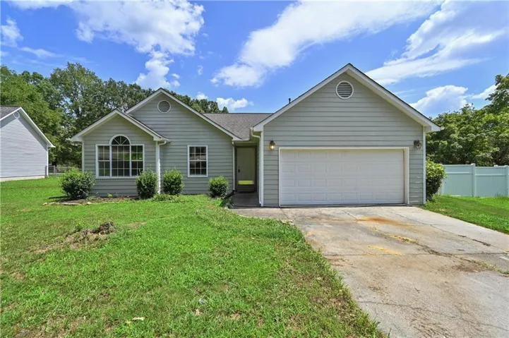 Single-story residence featuring light-colored siding, an attached garage, and a concrete driveway