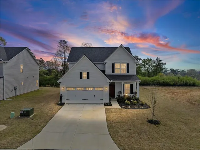 Two-story residence with white siding, dark shutters, an attached two-car garage, and a covered porch