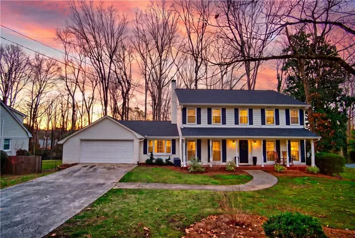 Two-story traditional residence with an attached two-car garage, covered front porch, and mature landscaping
