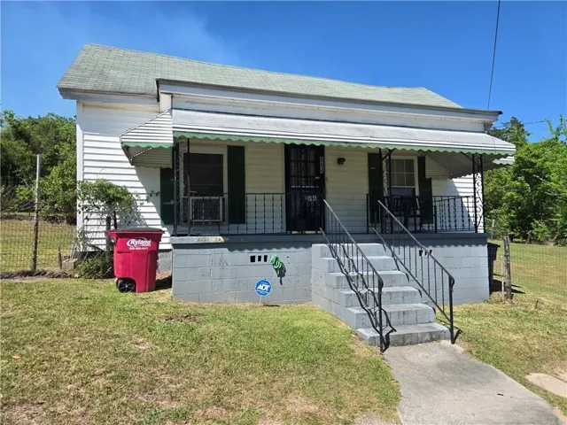 Porch with decorative wrought iron railing, concrete steps, and a scalloped awning