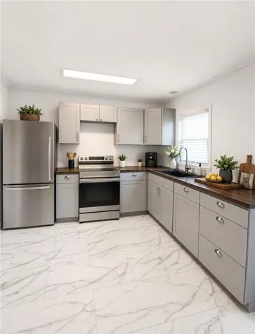 Modern kitchen featuring light gray cabinetry and wood-finish countertops