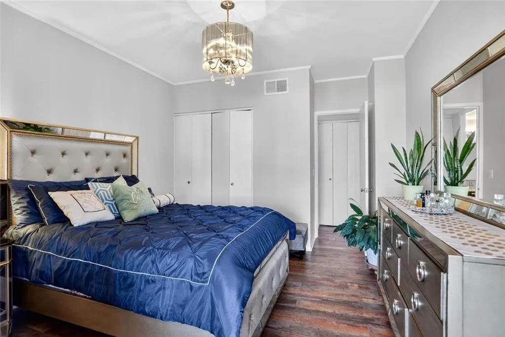 Bedroom featuring ornamental molding, dark wood-type flooring, a closet, and a chandelier