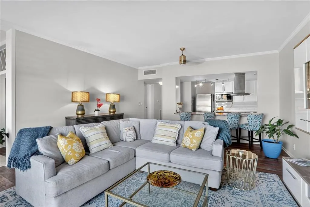 Living room with dark wood-type flooring and ornamental molding