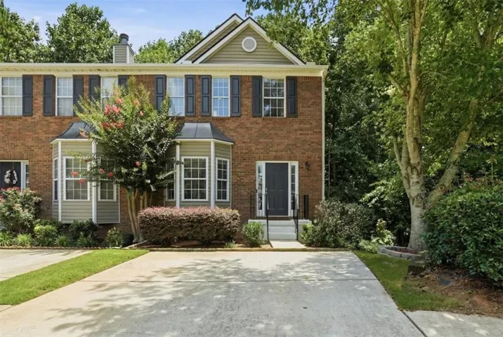 Brick townhouse exterior with a bay window, black shutters, and an elevated entryway