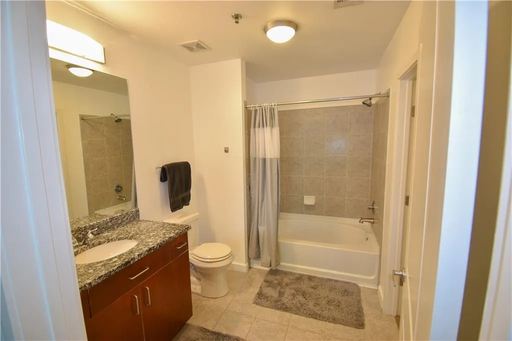 Bathroom featuring vanity, shower / bathtub combination with curtain, and light tile patterned flooring