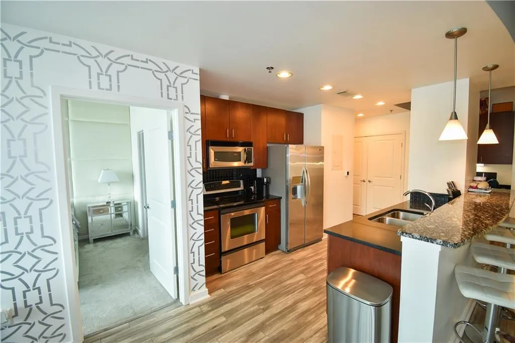 Kitchen featuring a breakfast bar, stainless steel appliances, pendant lighting, a peninsula, and light wood-type flooring