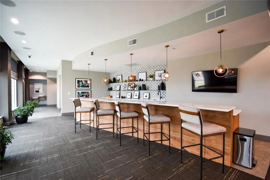 Bar area with light countertops and pendant lighting