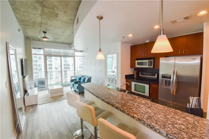 Kitchen with stainless steel appliances, a breakfast bar area, dark wood finished floors, dark stone countertops, and open floor plan