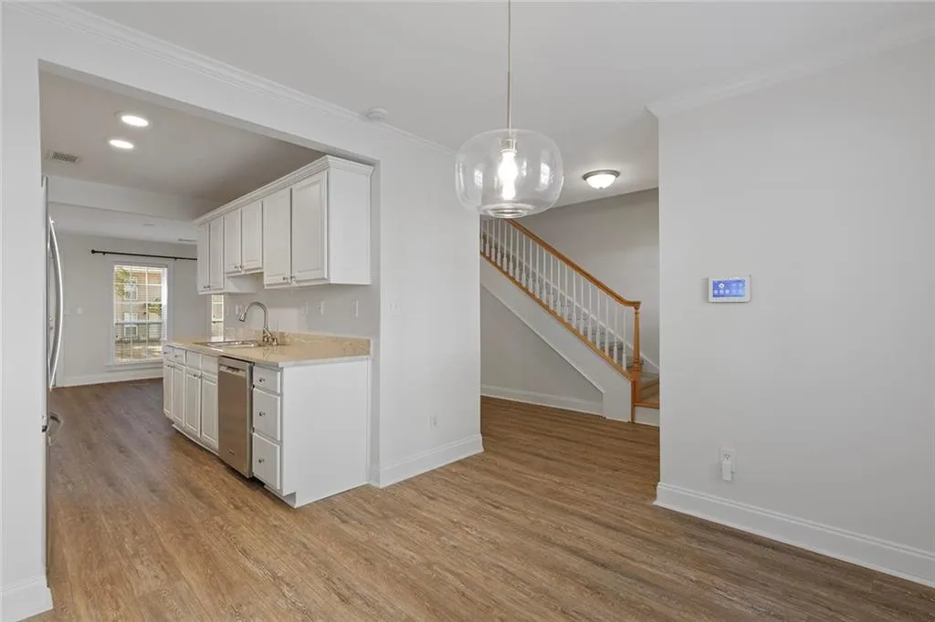Kitchen featuring baseboards, stainless steel dishwasher, light wood-type flooring, and white cabinets