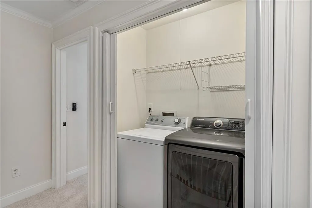 Laundry area with light colored carpet, ornamental molding, separate washer and dryer, laundry area, and baseboards