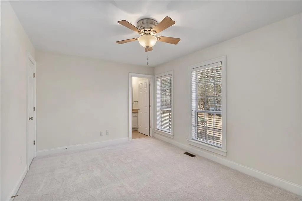 Bedroom with light carpet, ceiling fan, visible vents, and baseboards