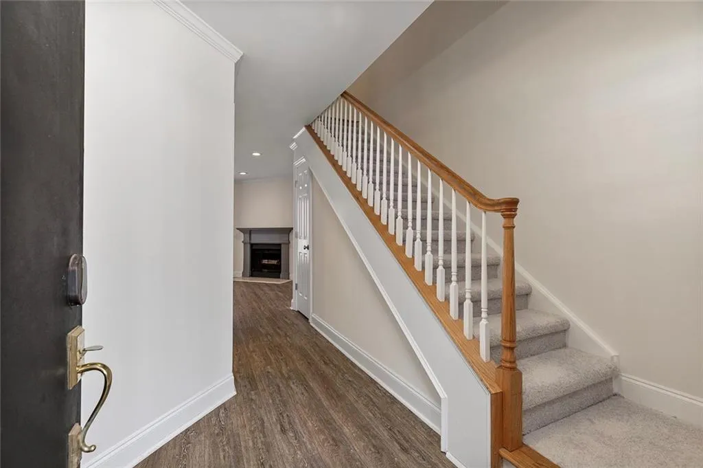 Staircase with recessed lighting, a fireplace with raised hearth, baseboards, and wood finished floors