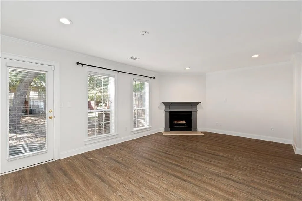 Living room with crown molding, a fireplace, and dark wood-style flooring
