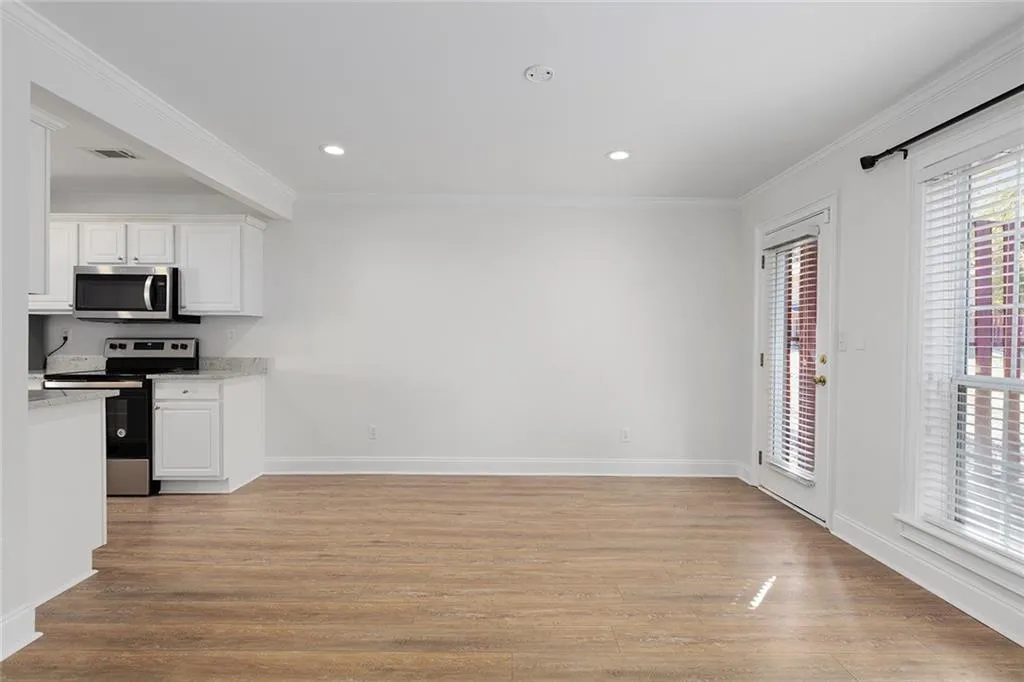 Kitchen featuring visible vents, white cabinetry, light wood-style floors, appliances with stainless steel finishes, and ornamental molding