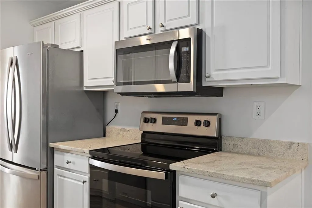 Kitchen featuring white cabinets, light stone countertops, and stainless steel appliances