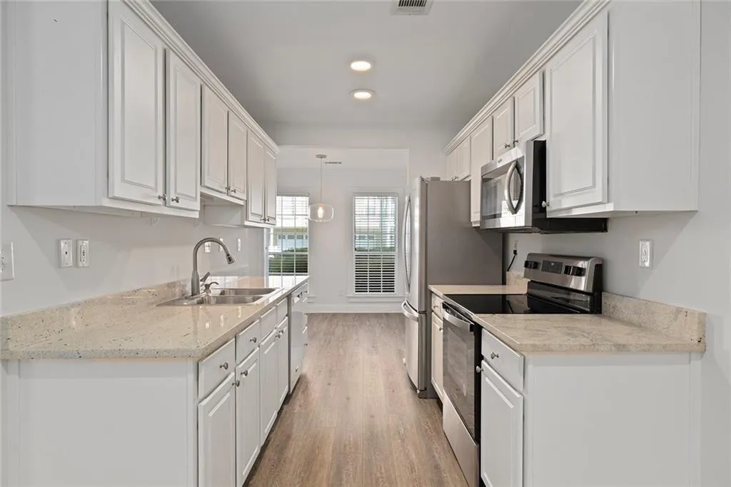 Kitchen with white cabinetry, stainless steel appliances, and a sink