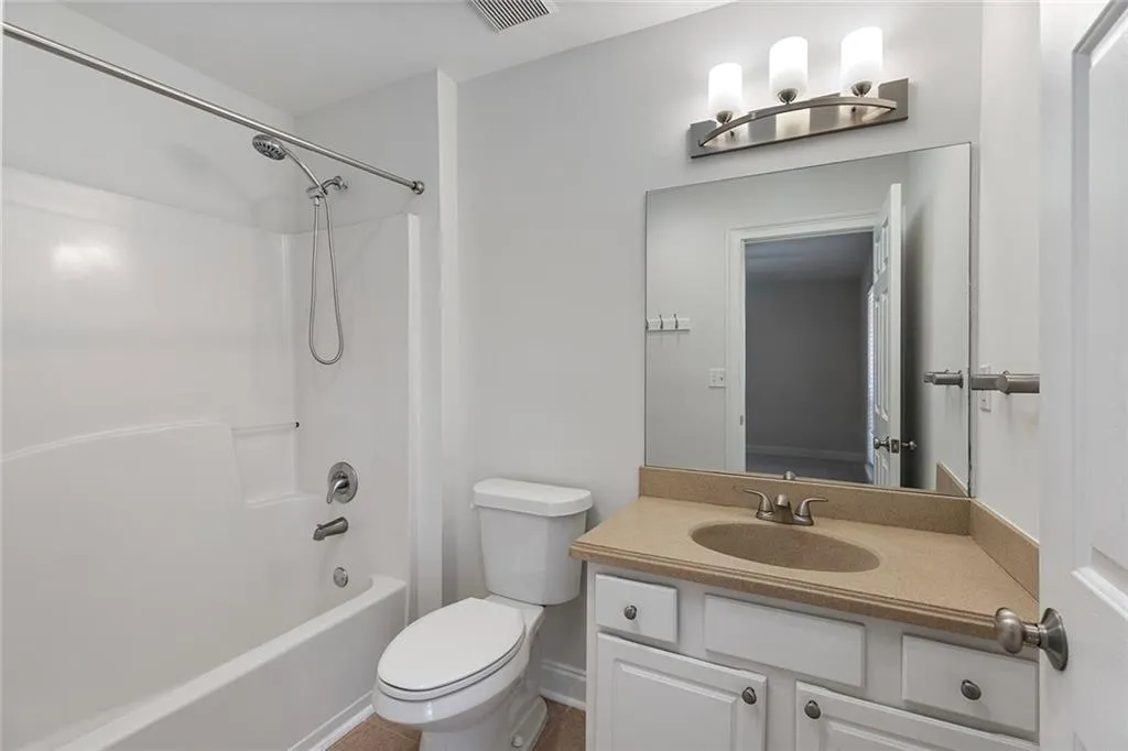 Bathroom with toilet, shower / washtub combination, visible vents, and vanity