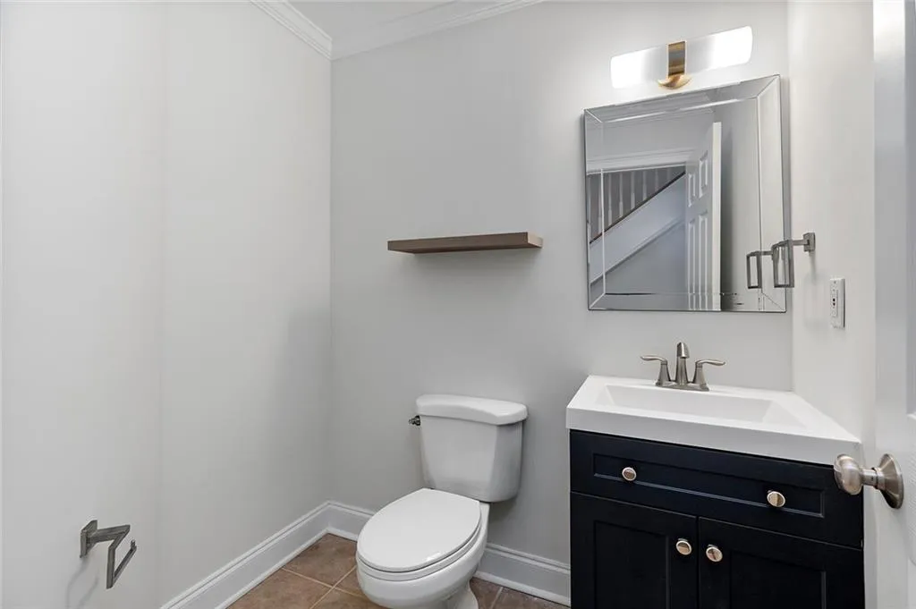 Bathroom featuring toilet, ornamental molding, vanity, baseboards, and tile patterned floors