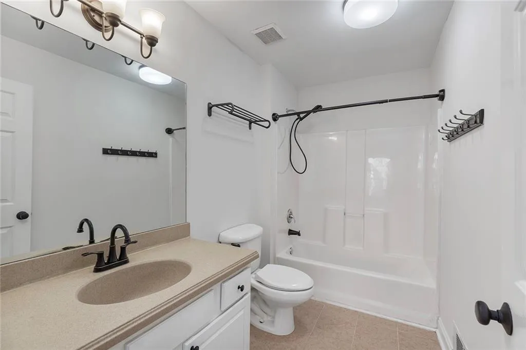 Bathroom featuring visible vents, toilet, washtub / shower combination, vanity, and tile patterned flooring