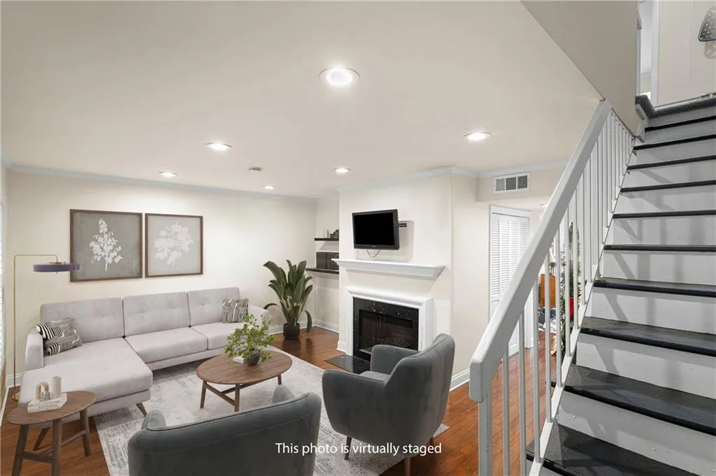 Living area featuring ornamental molding, a fireplace with flush hearth, dark wood-style flooring, and recessed lighting