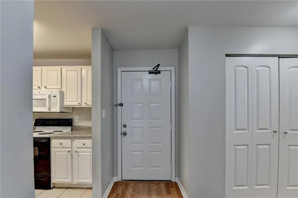 Kitchen featuring white appliances, white cabinets, and light wood-style floors