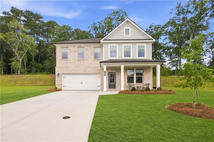Two-story residence featuring a brick and siding exterior, covered front porch, two-car garage, and a concrete driveway