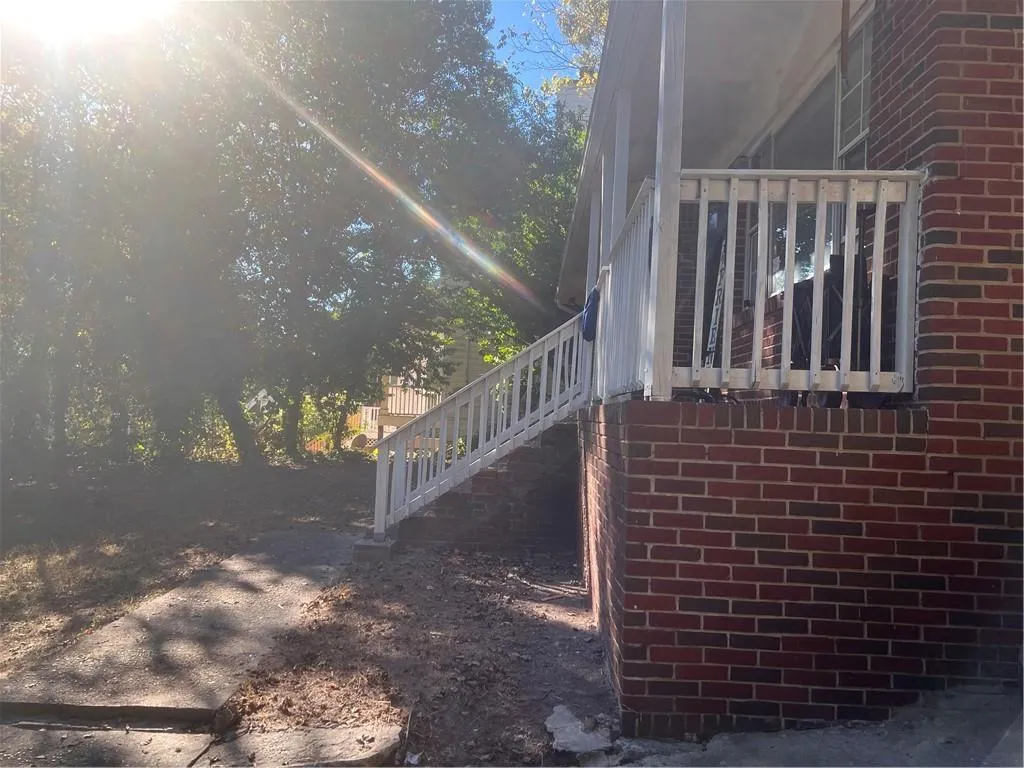 View of side of home featuring brick siding and stairway View of side of home featuring brick siding and stairway