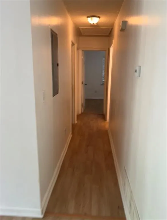 Hall featuring light wood-type flooring, attic access, and electric panel Hall featuring light wood-type flooring, attic access, and electric panel