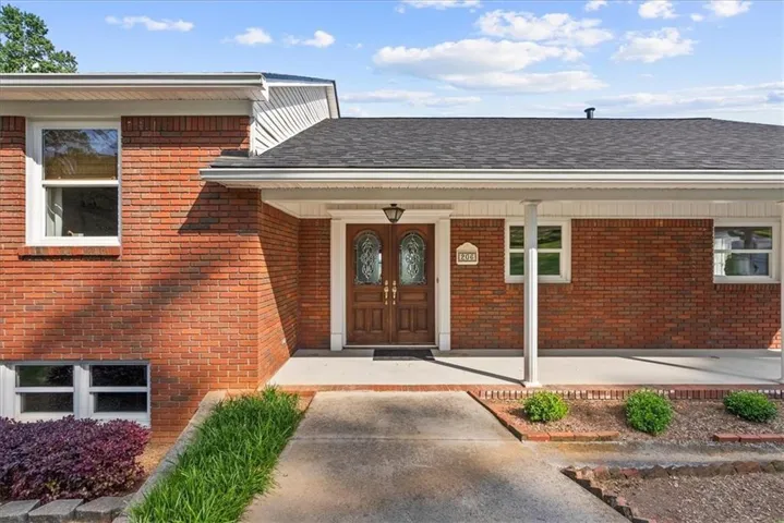 Brick exterior with a covered front porch and a dark shingle roof