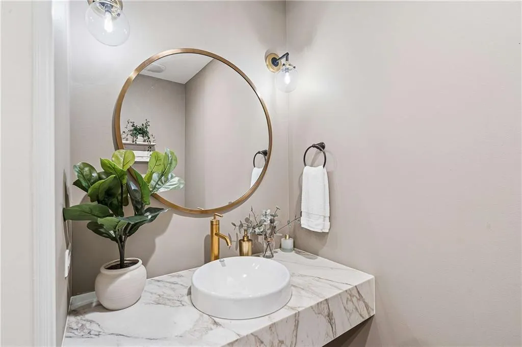 Floating vanity with a stone countertop, vessel sink, and gold-finish faucet