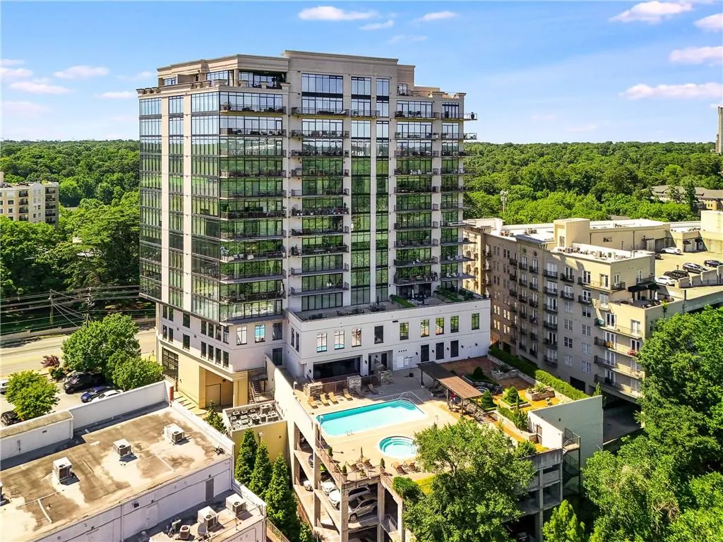 Modern high-rise building featuring extensive glass curtain walls, multiple balconies, a rooftop pool, and an integrated hot tub