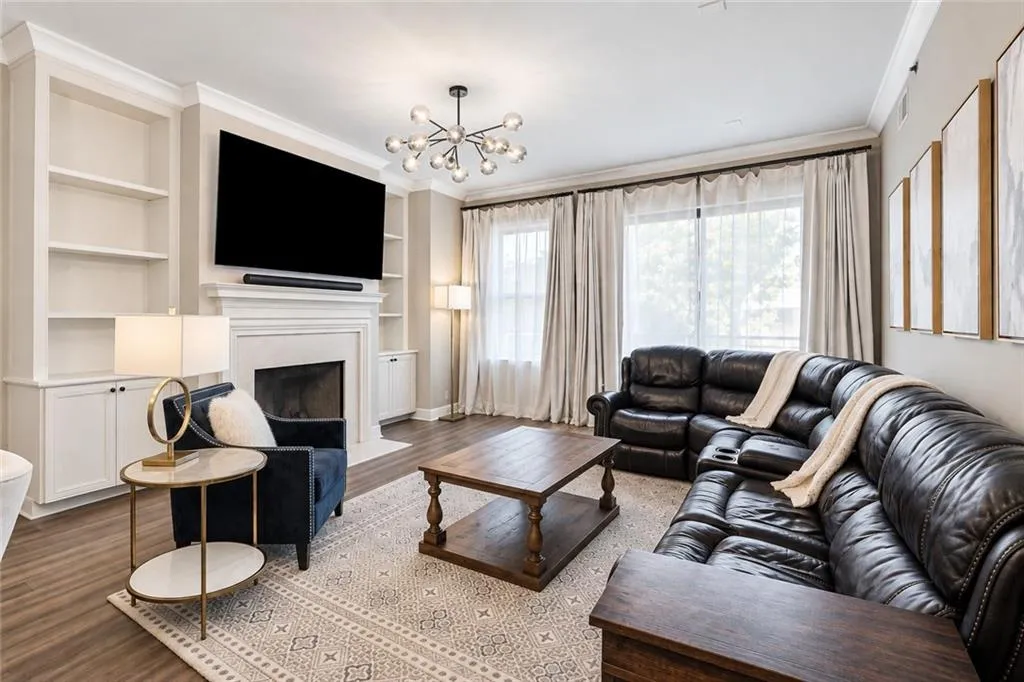 Living area with wood-finish flooring, a fireplace, and built-in shelving and cabinetry