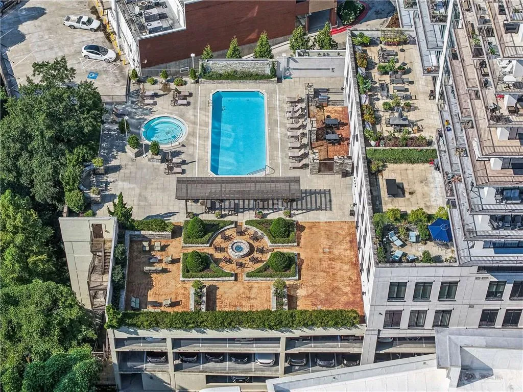 Rooftop amenity space featuring a rectangular pool, circular spa, a pergola-covered seating area, and manicured garden beds