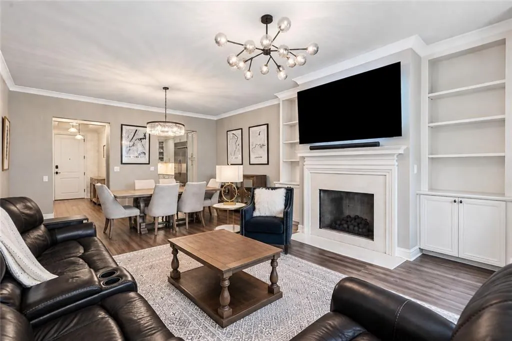 Spacious living area featuring wood-finish flooring, a fireplace with a mantel, and built-in shelving