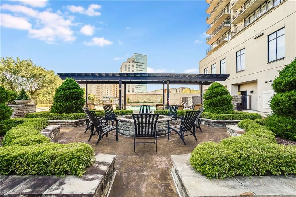 Landscaped patio featuring a stone-clad fire pit, a dark-stained wood pergola, and structured hedges