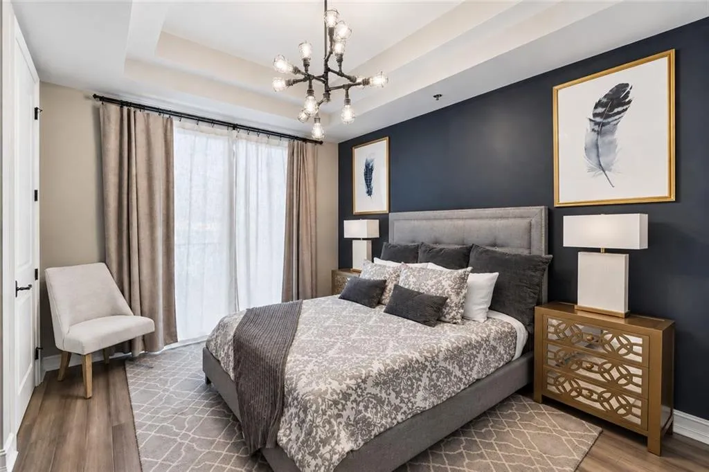 Tray ceiling with a decorative light fixture, wood-finish flooring, and a large sliding door with sheer and blackout curtains