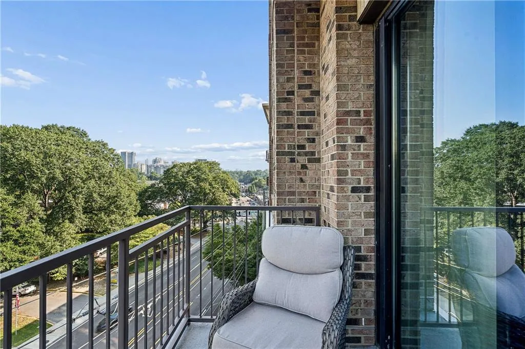 Private balcony featuring a metal railing, brick exterior, and large sliding glass door
