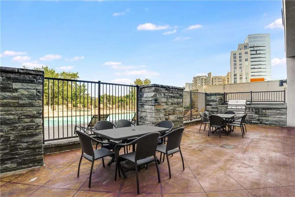 Expansive patio with stamped concrete flooring, stone-clad perimeter walls, and direct pool access