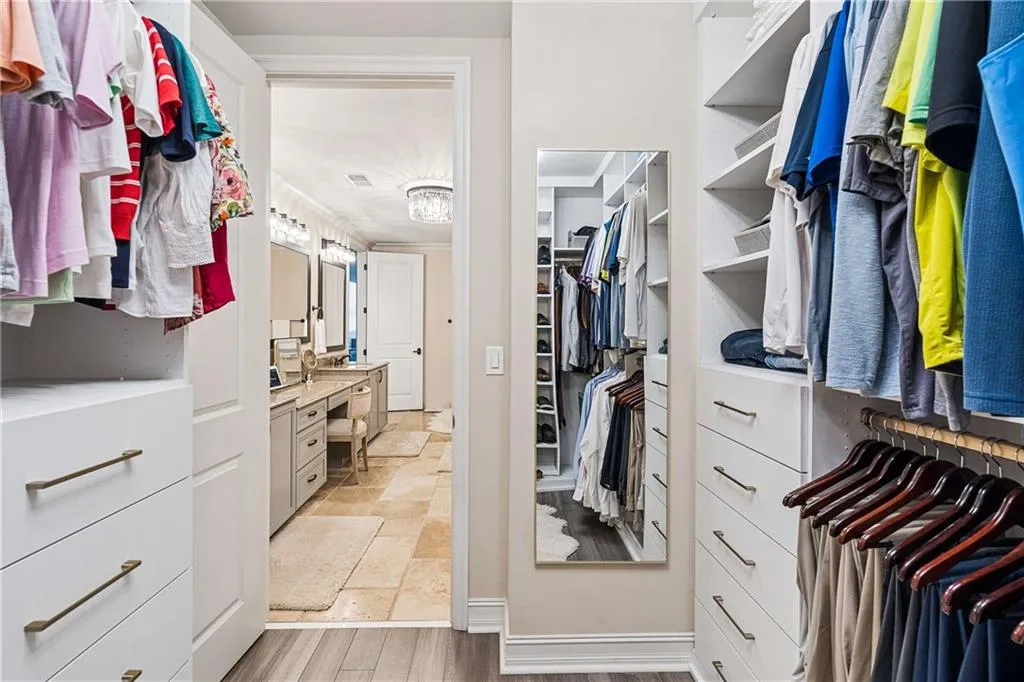 Custom closet system with integrated shelving and drawers, wood-finish flooring, and a full-length mirror