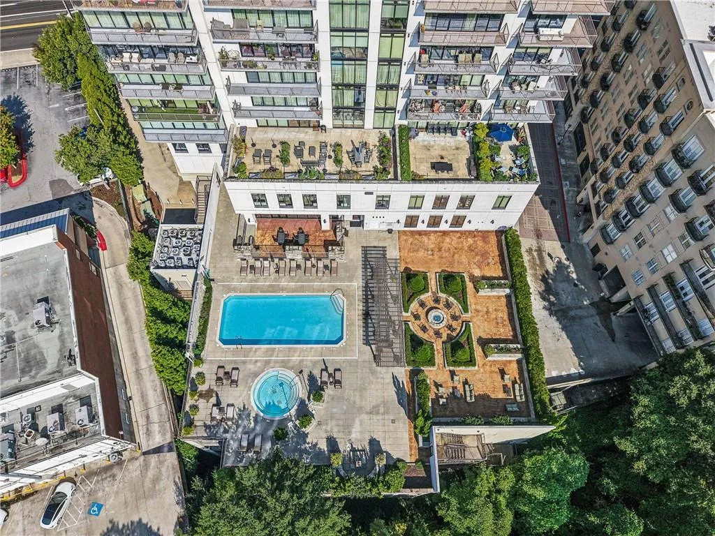 Building exterior featuring multiple private balconies, a rooftop terrace with planters, a rectangular swimming pool, a circular spa, and a formal garden with a central fountain