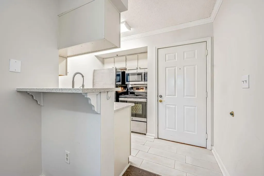 Kitchen with a breakfast bar, appliances with stainless steel finishes, crown molding, a peninsula, and a textured ceiling